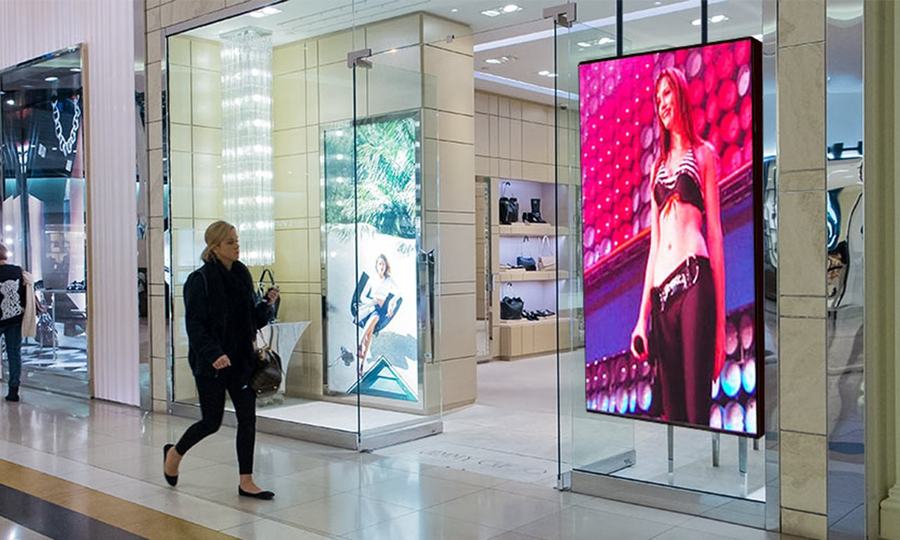 Vertical floor-standing LED totem in a shopping mall corridor